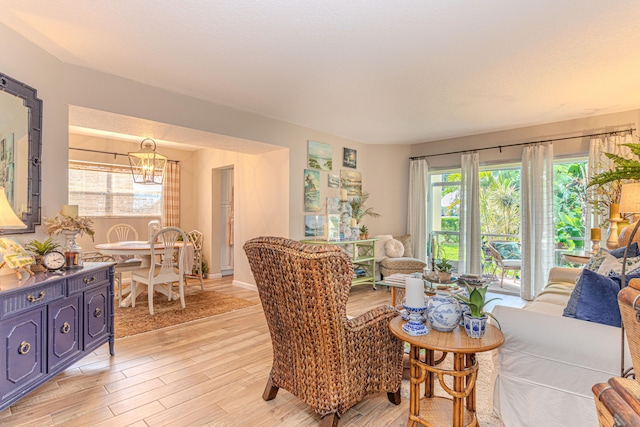 living room featuring a wealth of natural light, light hardwood / wood-style floors, and a notable chandelier