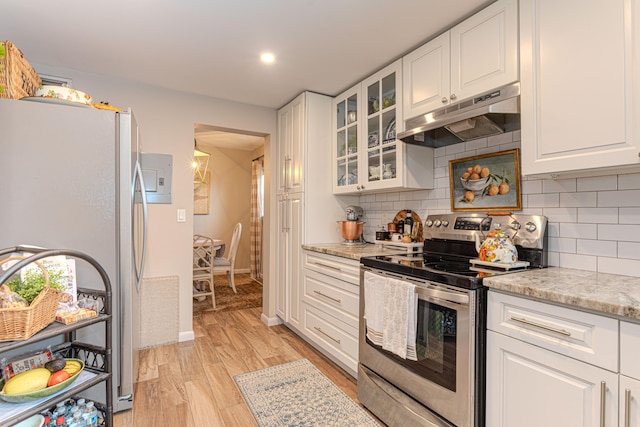 kitchen with light stone countertops, white cabinets, light wood-type flooring, and appliances with stainless steel finishes