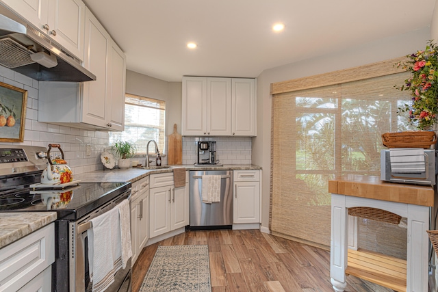 kitchen with light hardwood / wood-style flooring, white cabinetry, sink, tasteful backsplash, and stainless steel appliances