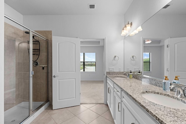 bathroom with a shower with door, vanity, and tile patterned flooring