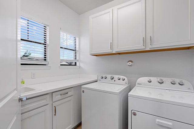 clothes washing area with washer and clothes dryer and cabinets