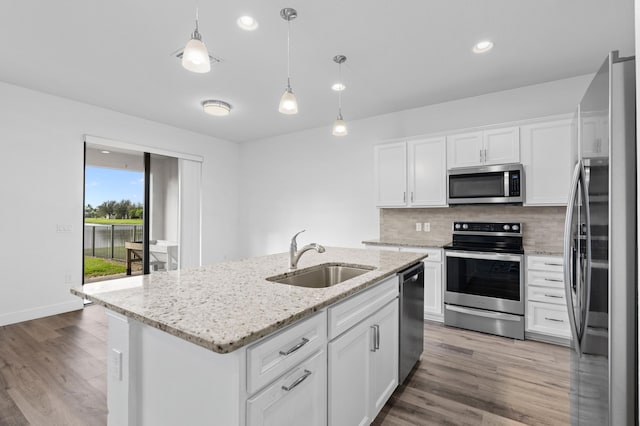 kitchen with a center island with sink, sink, white cabinets, decorative light fixtures, and appliances with stainless steel finishes