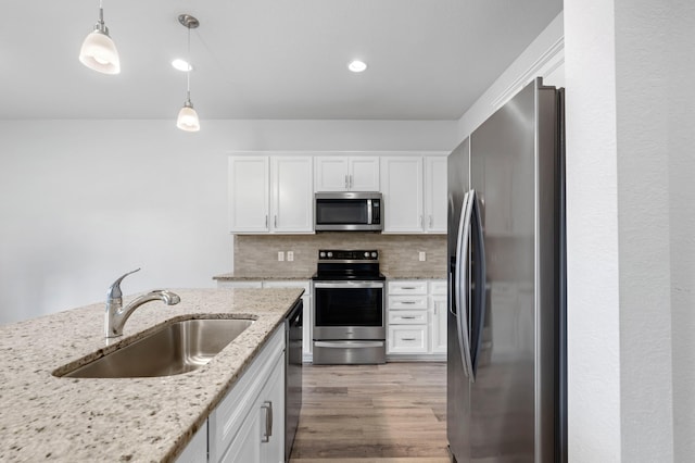 kitchen featuring white cabinets, backsplash, sink, pendant lighting, and stainless steel appliances