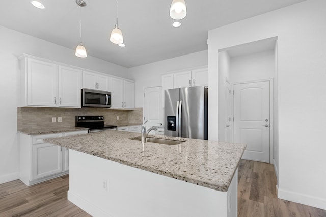 kitchen featuring white cabinets, an island with sink, appliances with stainless steel finishes, light hardwood / wood-style flooring, and sink