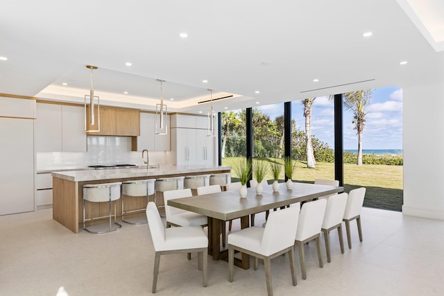 dining room with sink, a raised ceiling, and expansive windows