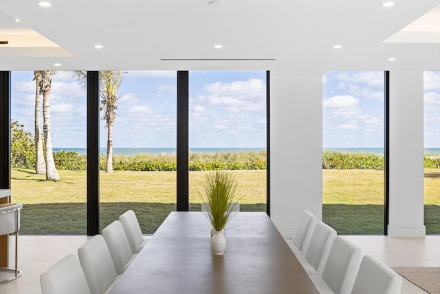 dining room featuring a water view, floor to ceiling windows, and light tile patterned flooring