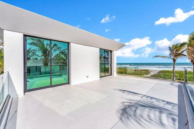 view of patio / terrace featuring a water view and a beach view