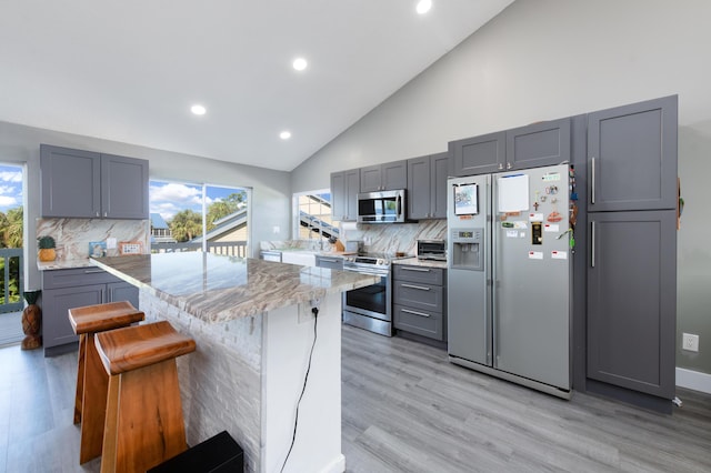 1441 NE 14th Ct Unit 4, Jensen Beach, FL 34957 - kitchen featuring appliances with stainless steel finishes, gray cabinetry, light stone countertops, recessed lighting, and high vaulted ceiling