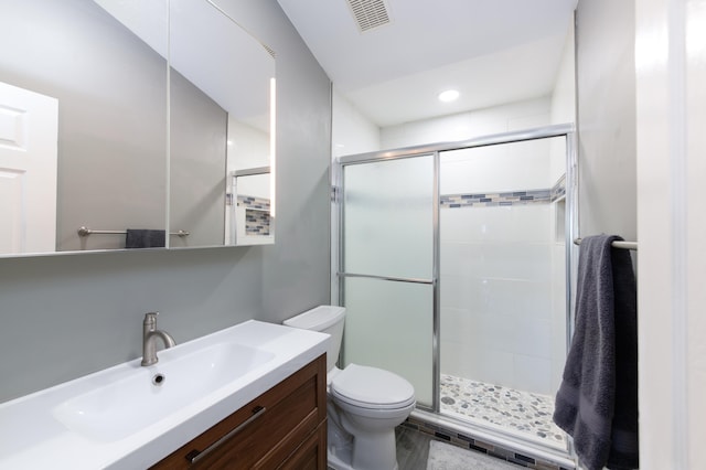 bathroom featuring toilet, vanity, and a shower with shower door