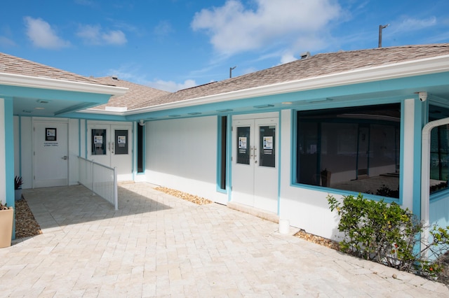 1441 NE 14th Ct Unit 4, Jensen Beach, FL 34957 - view of exterior entry with french doors and a shingled roof