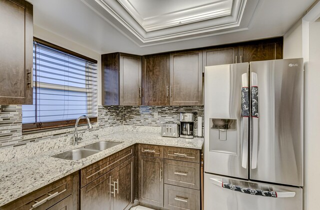 kitchen with sink, appliances with stainless steel finishes, a tray ceiling, dark brown cabinets, and light stone counters