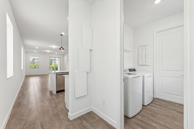 corridor with washing machine and clothes dryer, electric panel, and light hardwood / wood-style floors