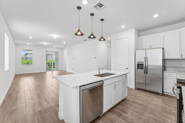 kitchen featuring a center island with sink, sink, white cabinetry, and stainless steel appliances