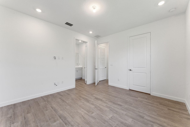 unfurnished bedroom featuring light wood-type flooring and ensuite bath