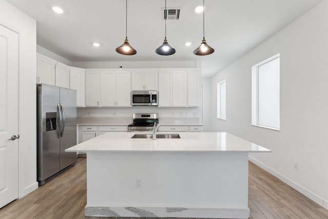 kitchen with decorative light fixtures, stainless steel appliances, white cabinetry, and light stone counters