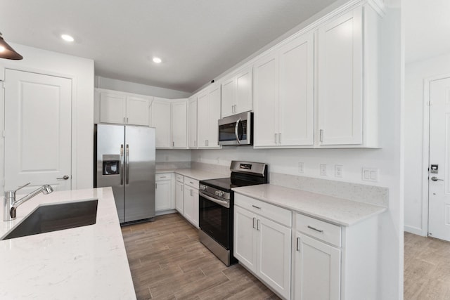 kitchen with light stone countertops, sink, white cabinetry, and stainless steel appliances