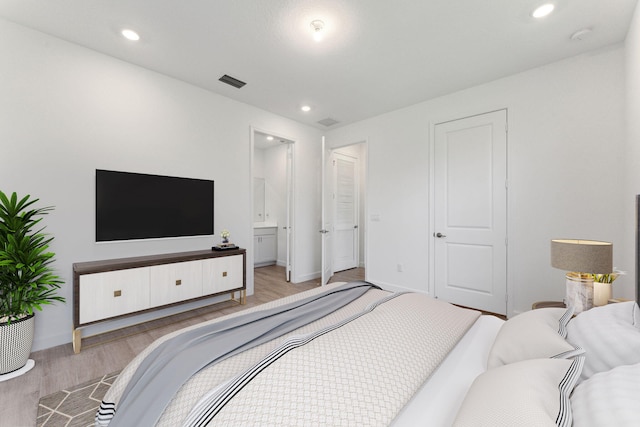 bedroom featuring ensuite bathroom and light hardwood / wood-style floors