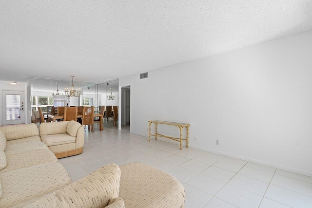 living room featuring a chandelier, a textured ceiling, and light tile patterned floors