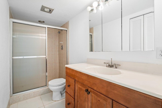 bathroom featuring toilet, vanity, tile patterned floors, and a shower with door