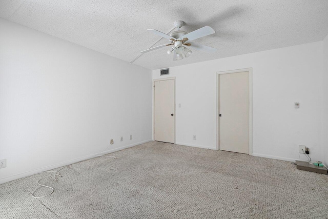 carpeted spare room with a textured ceiling and ceiling fan