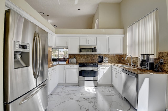 kitchen featuring white cabinetry, sink, appliances with stainless steel finishes, dark stone counters, and a textured ceiling