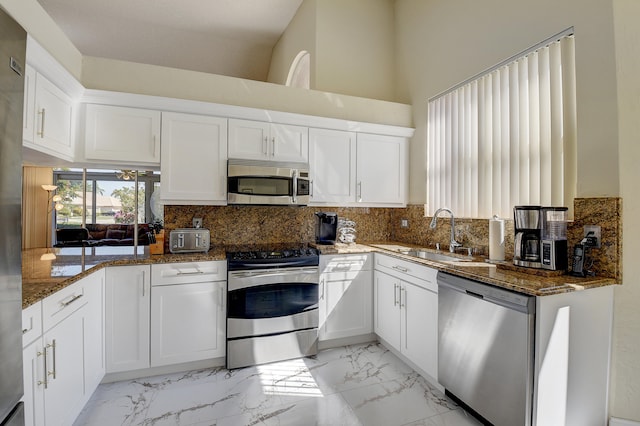 kitchen featuring dark stone countertops, white cabinetry, sink, and stainless steel appliances