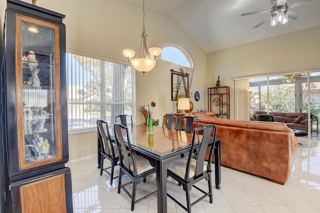 dining area with ceiling fan with notable chandelier, light tile patterned floors, and vaulted ceiling