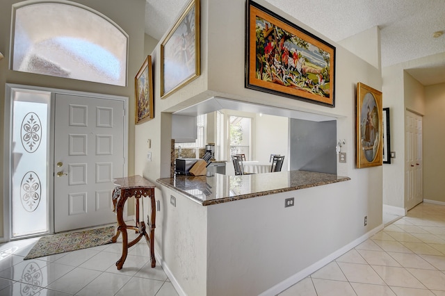 entryway with a textured ceiling and light tile patterned floors