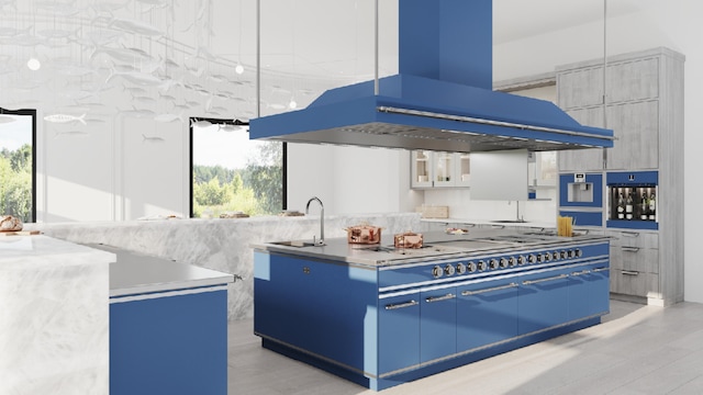 kitchen featuring blue cabinetry, sink, a center island, hanging light fixtures, and custom exhaust hood