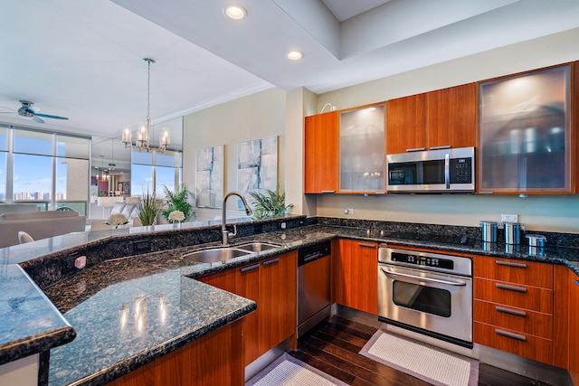 kitchen with stainless steel appliances, sink, dark stone counters, dark hardwood / wood-style floors, and pendant lighting