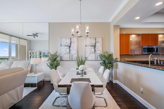 dining room featuring dark wood-type flooring, ceiling fan with notable chandelier, sink, and ornamental molding