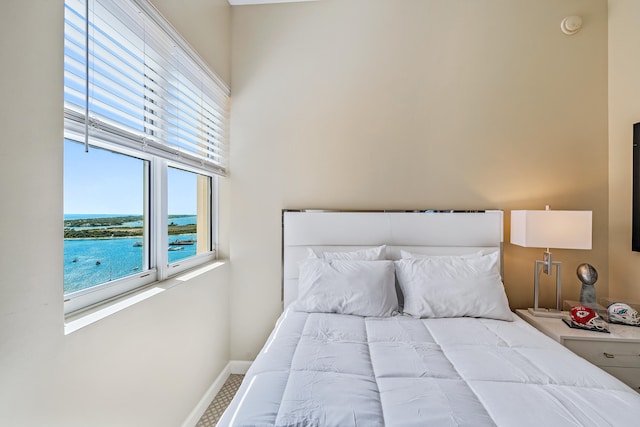 bedroom featuring a water view, carpet flooring, and a towering ceiling