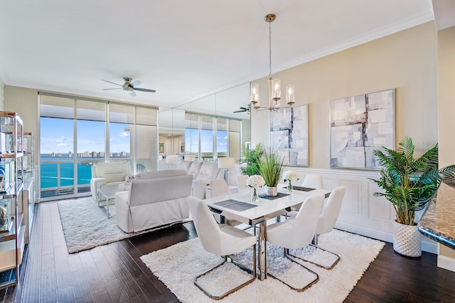 dining area with a water view, floor to ceiling windows, ceiling fan with notable chandelier, crown molding, and dark wood-type flooring