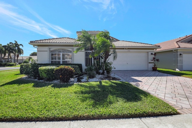 view of front of home with stucco siding, a front lawn, a garage, a tile roof, and decorative driveway