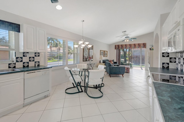 kitchen with backsplash, lofted ceiling, white appliances, white cabinets, and ceiling fan with notable chandelier