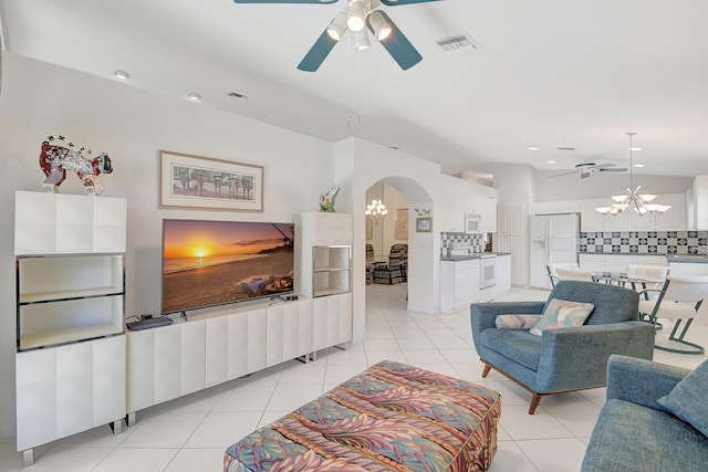 living area with ceiling fan with notable chandelier, arched walkways, visible vents, and light tile patterned floors