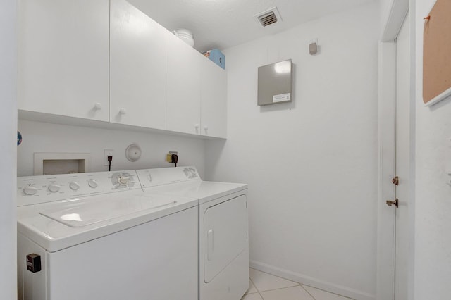 clothes washing area with cabinets, light tile patterned floors, a textured ceiling, and separate washer and dryer