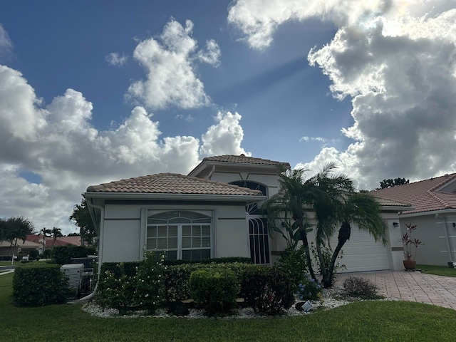 view of front of property featuring central AC unit, a garage, and a front yard