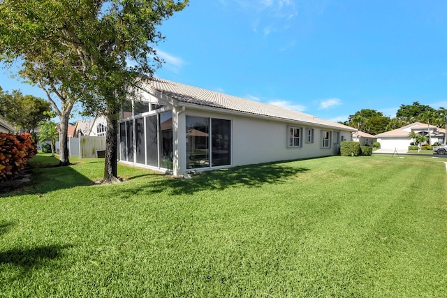 rear view of property with stucco siding, a lawn, and a tiled roof