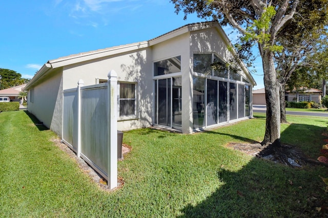 back of house with a yard, a sunroom, and stucco siding