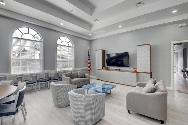 living room with light wood-type flooring, a raised ceiling, and visible vents