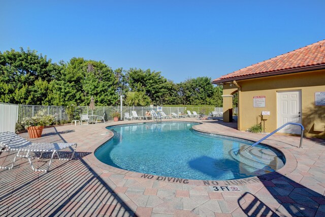 view of swimming pool featuring a patio, fence, and a hot tub