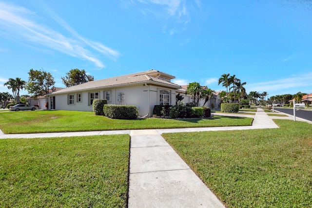 view of front of property with a tiled roof, a front lawn, and stucco siding