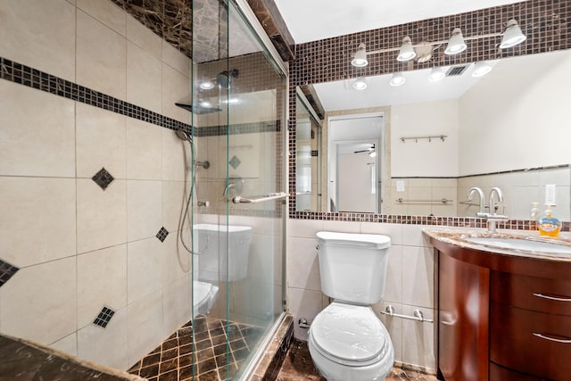 bathroom with ceiling fan, walk in shower, toilet, vanity, and tile walls