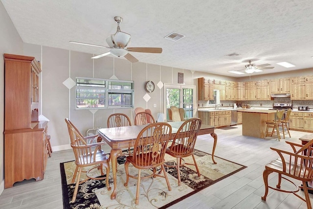 dining area featuring a textured ceiling, a healthy amount of sunlight, sink, and ceiling fan