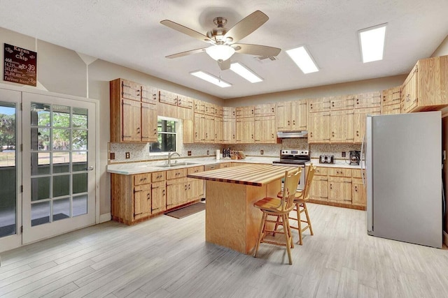 kitchen with sink, a center island, stainless steel appliances, and light hardwood / wood-style floors