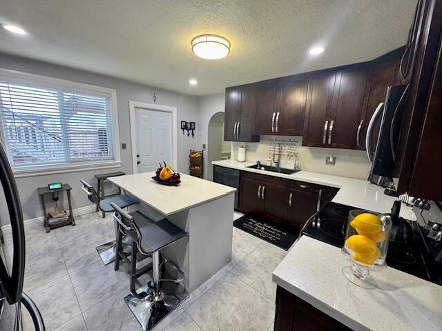 kitchen featuring a breakfast bar area, a textured ceiling, sink, and a kitchen island