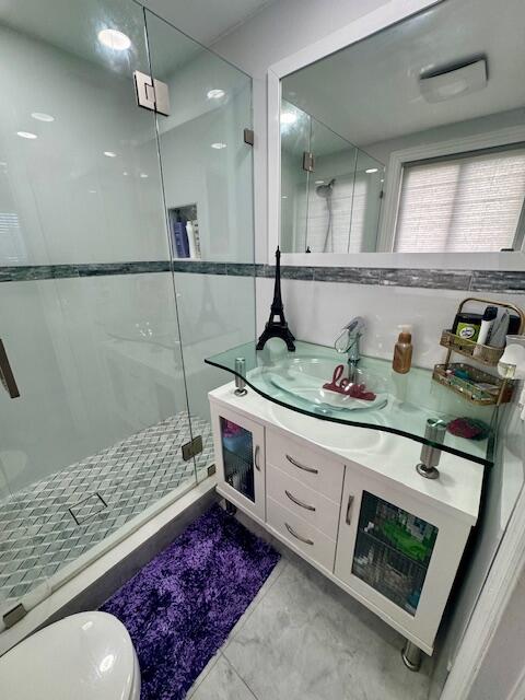 bathroom with toilet, vanity, and an enclosed shower