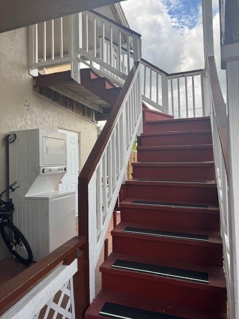 stairs featuring stacked washer / drying machine