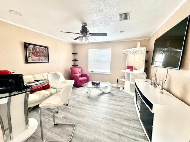 office with ornamental molding, a textured ceiling, hardwood / wood-style flooring, and ceiling fan